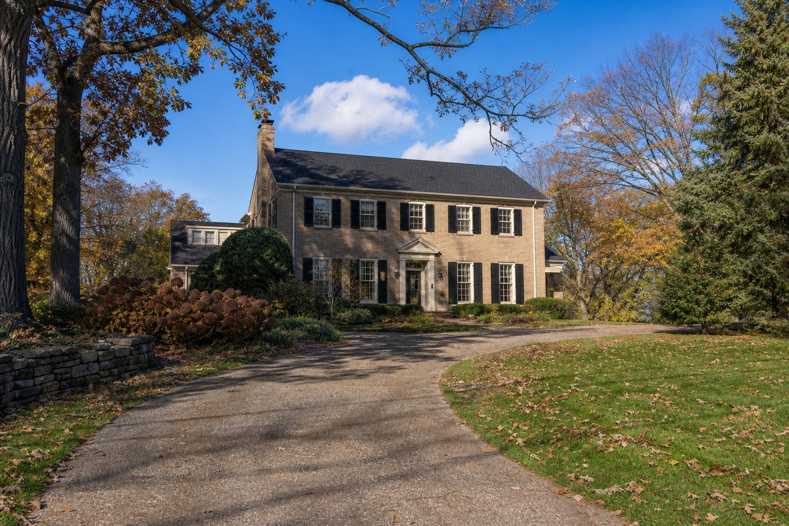 Tan-brick 1950s colonial home with centered entry and mature trees on Monroe Street in Madison's Near West Side.